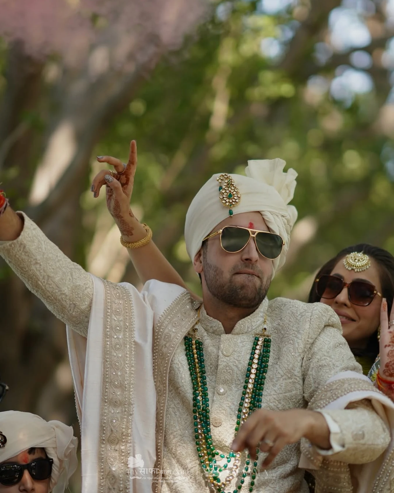 Groom in an ivory wedding safa with emerald jewellery for baraat pagri service in Hyderabad